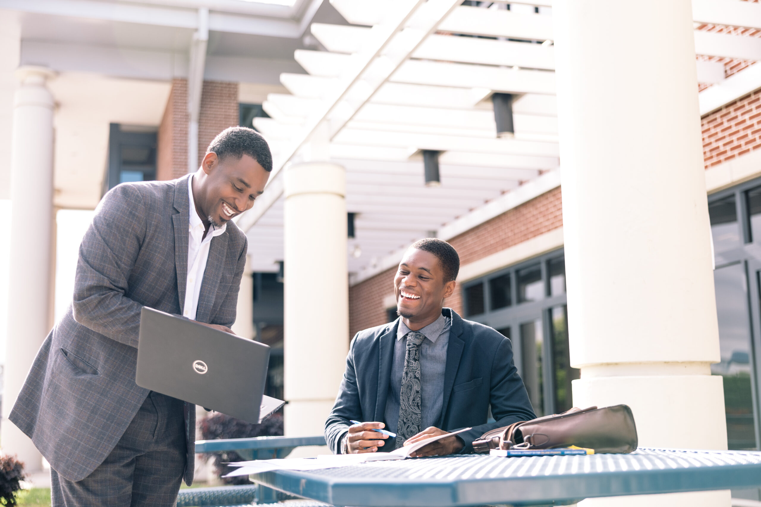 Professor with student on laptop outside engaged in Continuous Improvement Strategies for Advancing Quality Digital Learning.