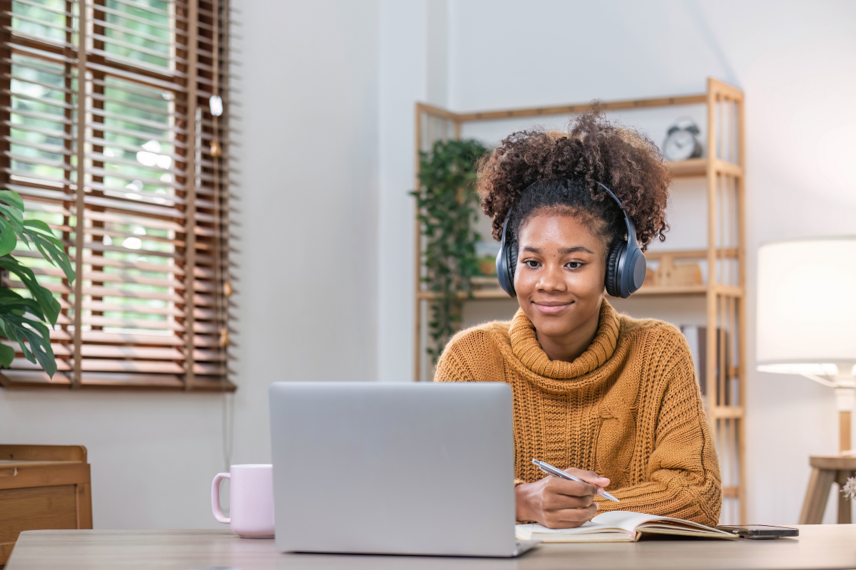 Female student on laptop with headphones on using adaptive learning implementation