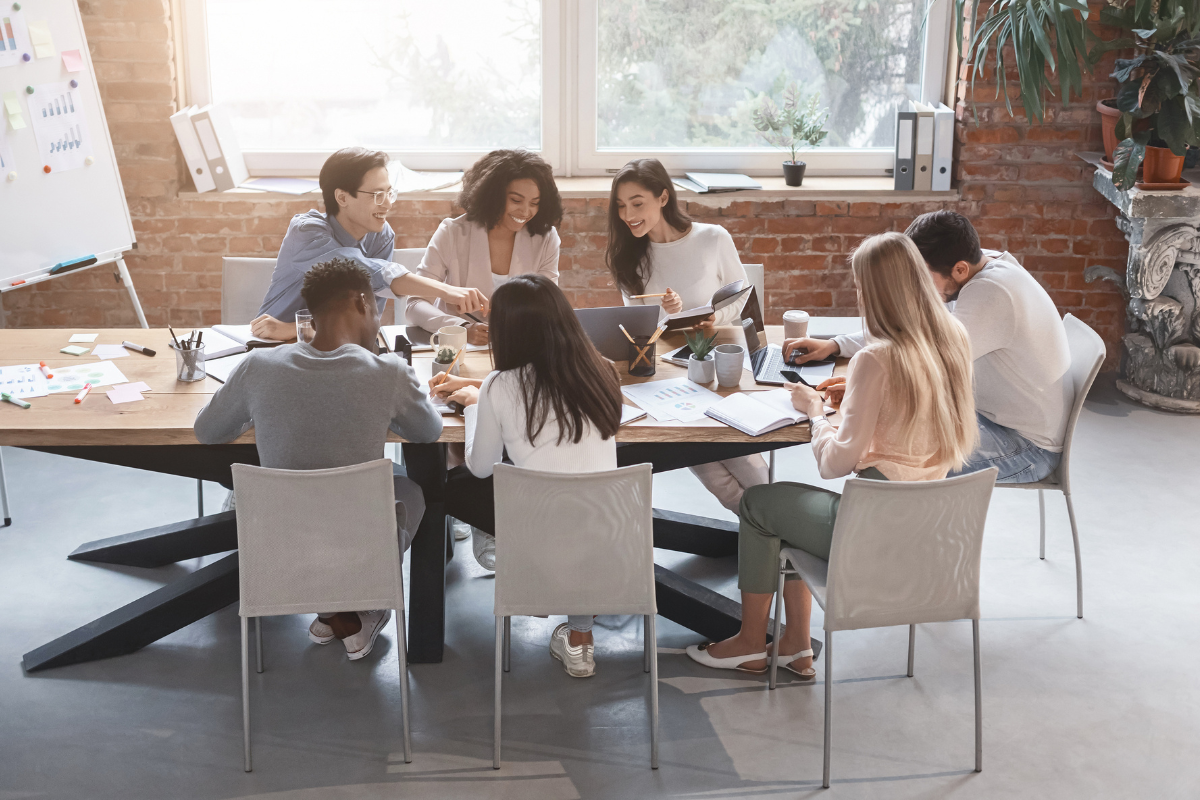 A group of faculty sitting around a wooden table in a modern office, engaged in a discussion on implementing digital learning tools.
